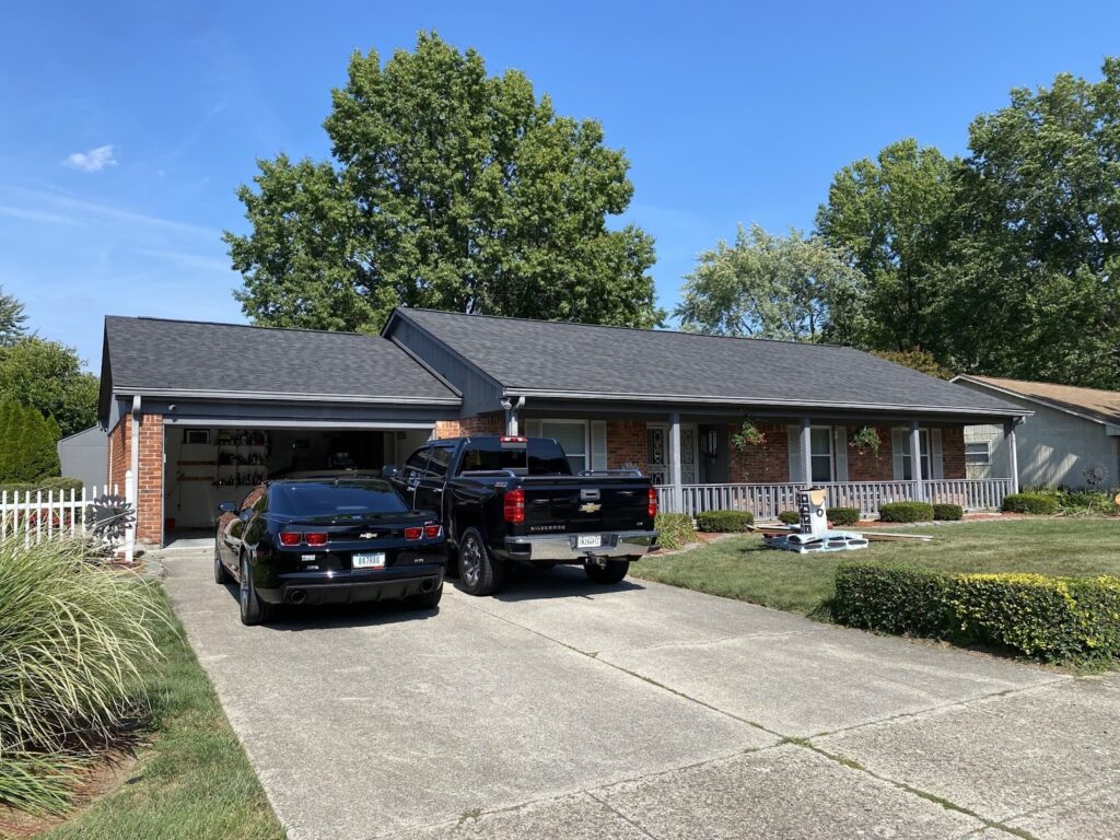 A home with a dark-colored roof and two vehicles in the driveway
