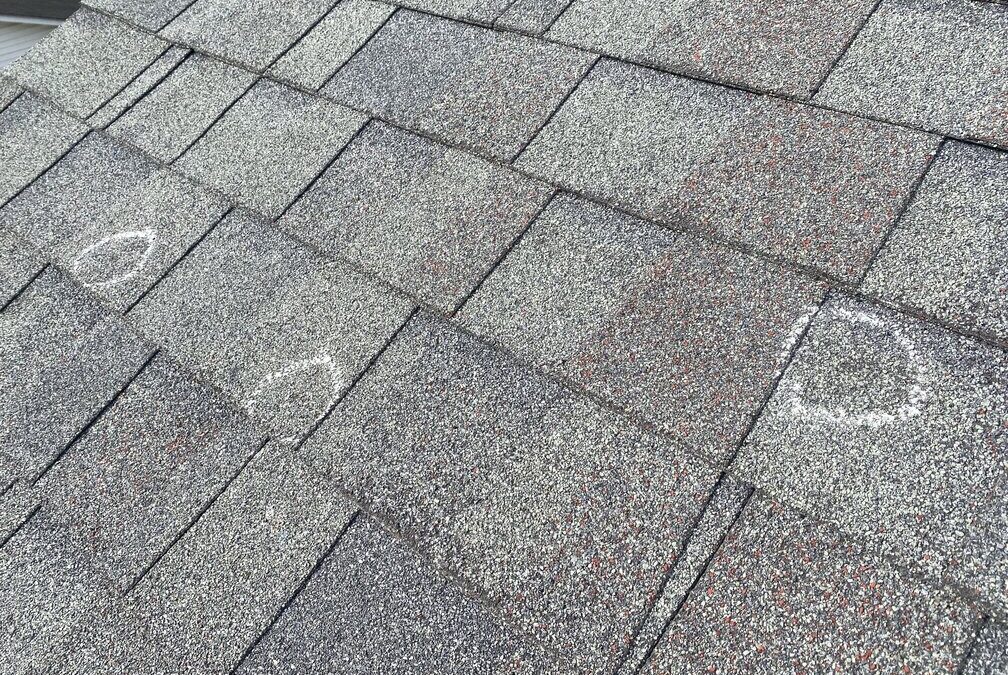A shingle roof marked with chalk to indicate damage during an inspection