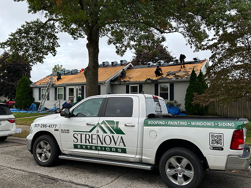 A Strenova commercial truck parked in the foreground as the team works on a roof in the background