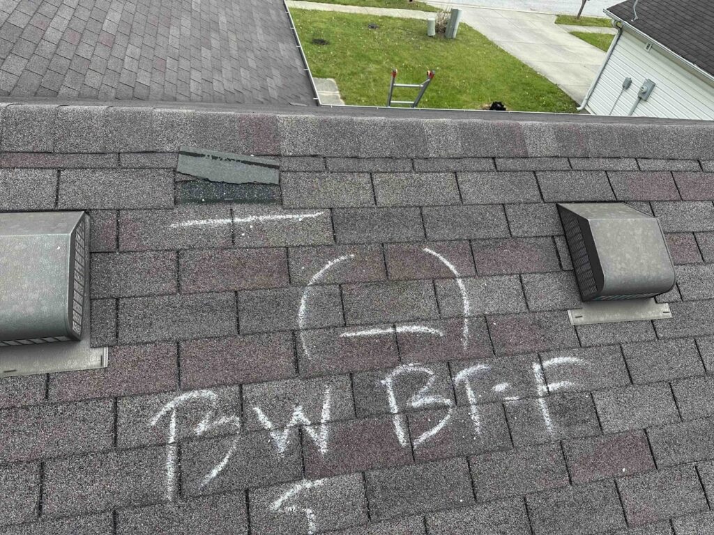  A shingle roof is marked with letters and symbols during inspection
